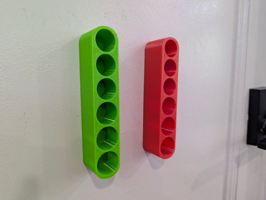Green and red wall-mounted holders on a white wall.